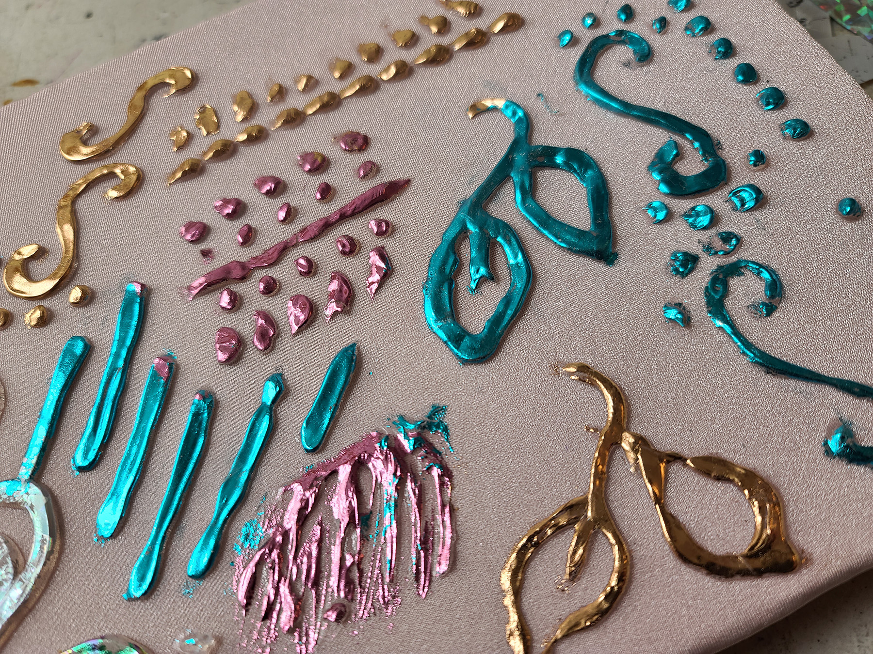 Several shiny foil embossing designs in bright metallic colours, on stretched pink spandex.