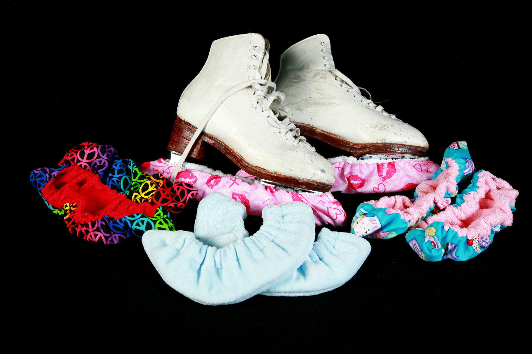 Several pairs of figure skate soakers, surrounding a pair of skates.